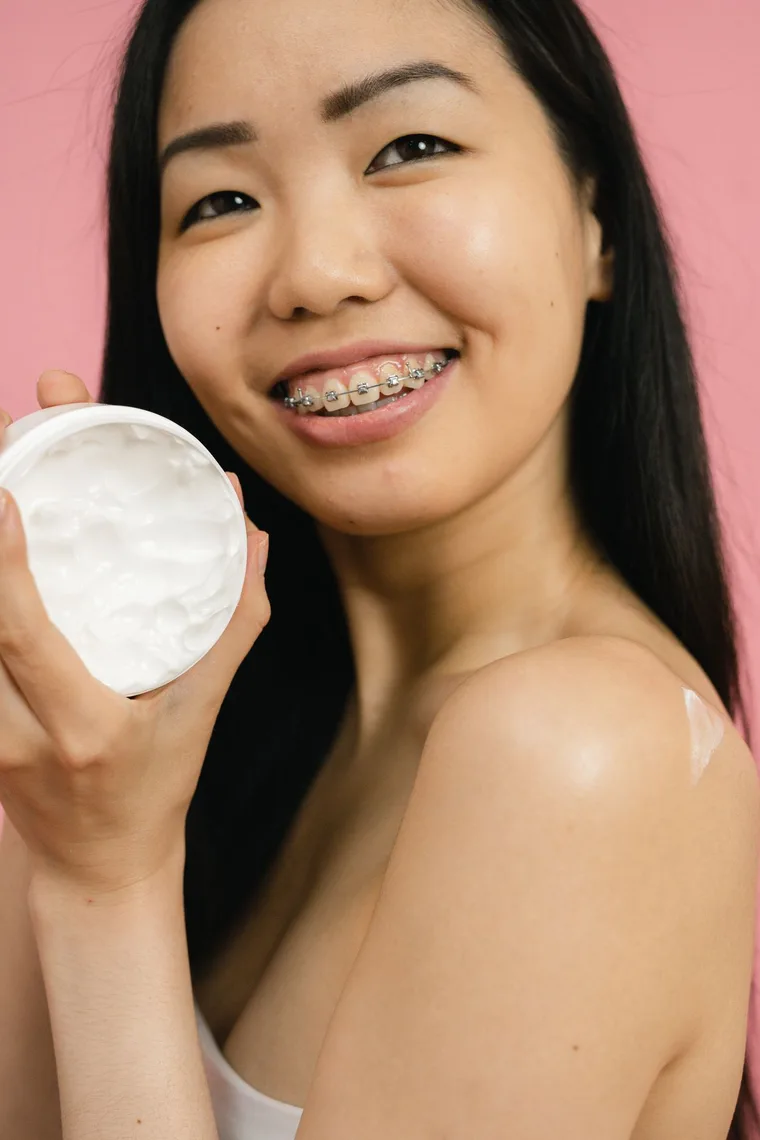 Smiling Asian woman holding a skincare moisturiser