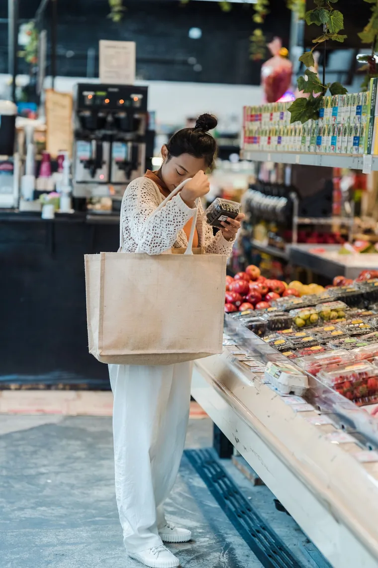 Asian woman choosing fresh groceries with a reusable tote bag