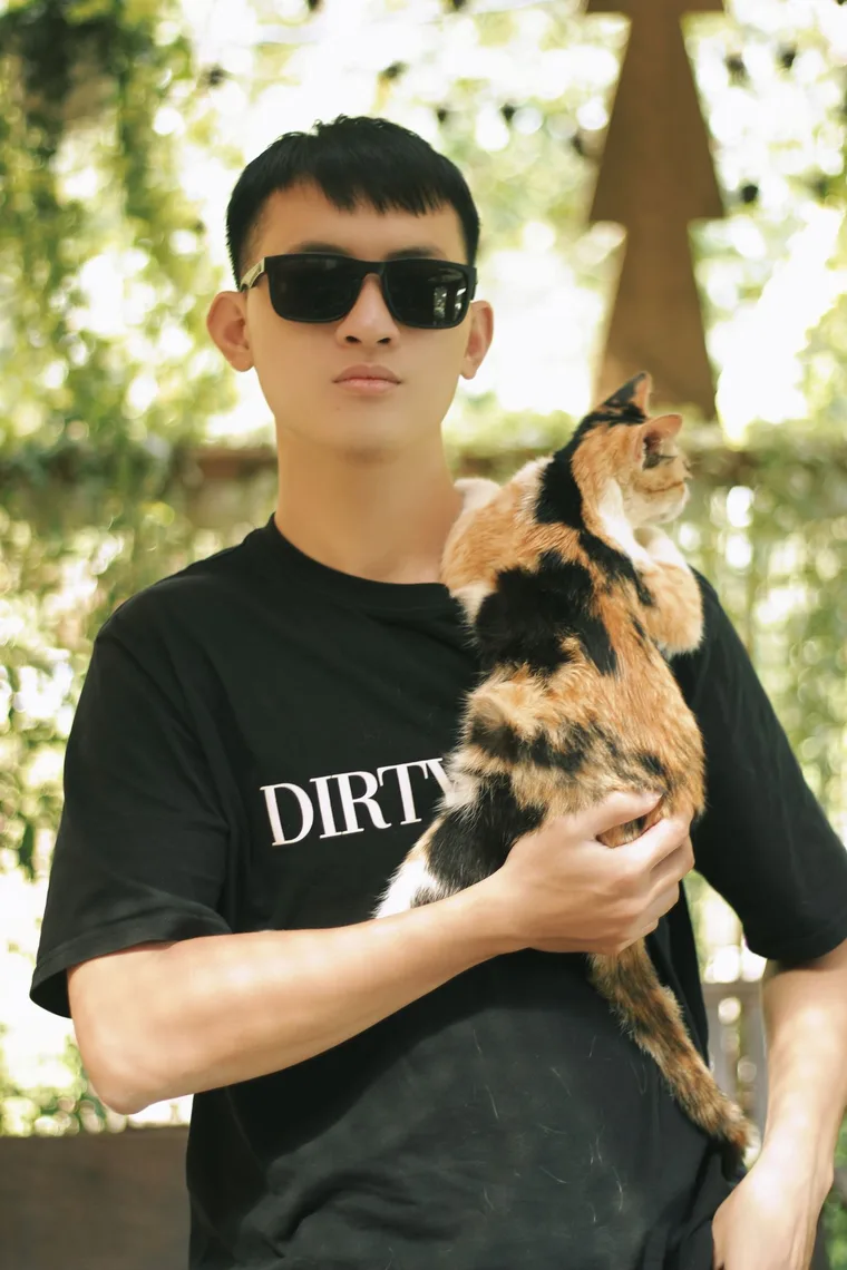 Young Asian pet owner holding a calico cat outdoors